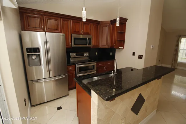 a kitchen with stainless steel appliances granite countertop a refrigerator a stove and a sink with wooden floor