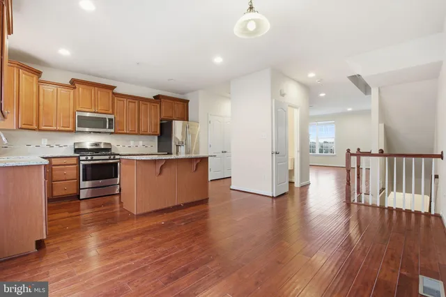 a kitchen with stainless steel appliances granite countertop a stove top oven a sink and a refrigerator