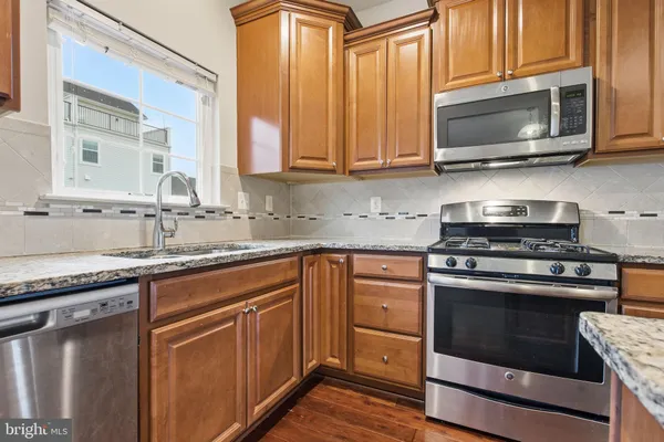 a kitchen with stainless steel appliances granite countertop a stove microwave and sink