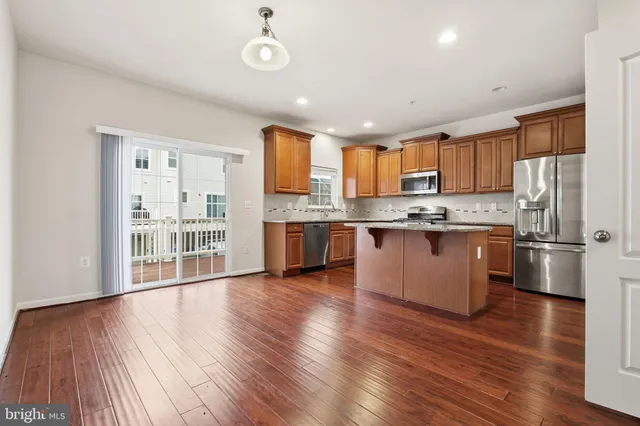 a kitchen with stainless steel appliances granite countertop a refrigerator a stove top oven a sink and cabinets with wooden floor