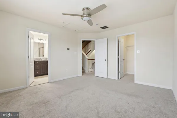 an empty room with chandelier fan and windows