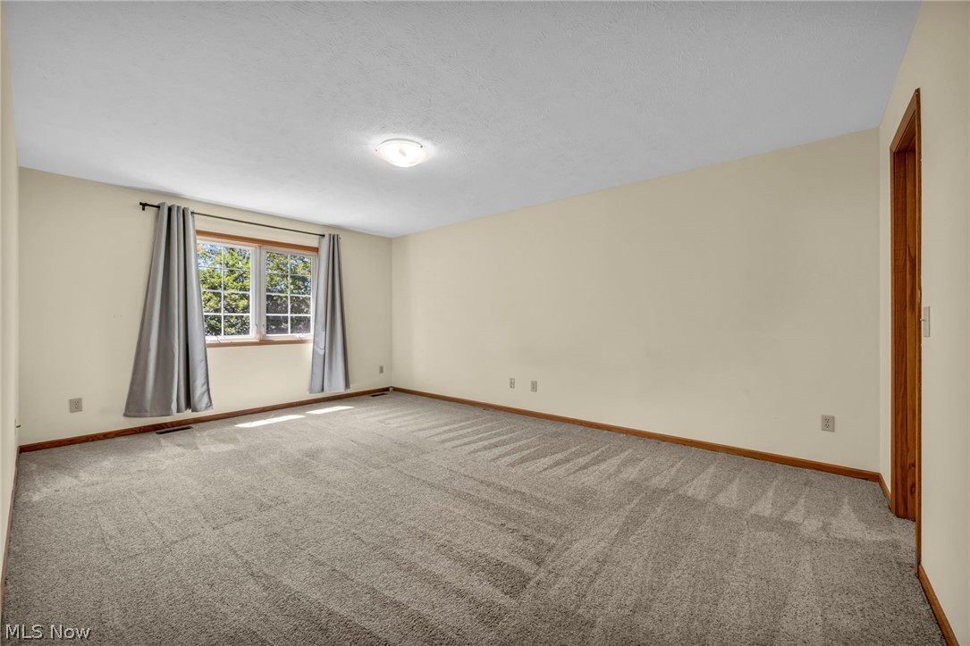 9842 Johnnycake Ridge Road Mentor, OH 44060 - Photo 22 of 40 Spacious room featuring neutral carpeting, light-toned walls, and a large window with white muntins