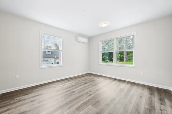 an empty room with wooden floor and windows