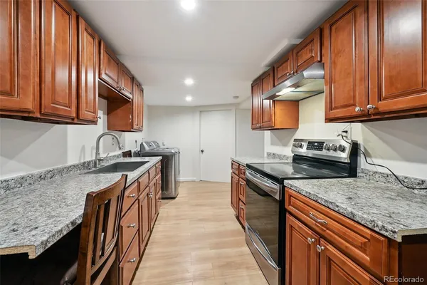 a kitchen with granite countertop stainless steel appliances a sink dishwasher a stove top oven a refrigerator and dishwasher