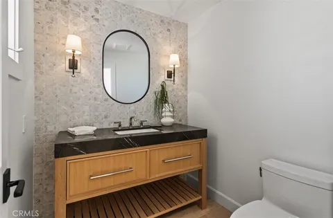 a bathroom with a granite countertop toilet a sink and a mirror