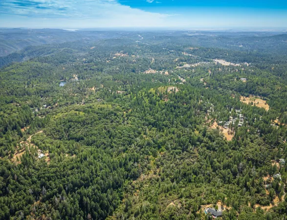 an aerial view of residential houses with outdoor space and trees