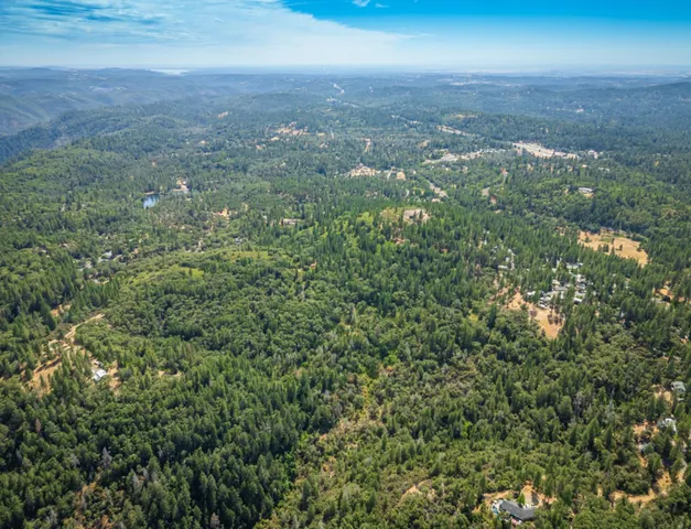 an aerial view of residential houses with outdoor space and trees