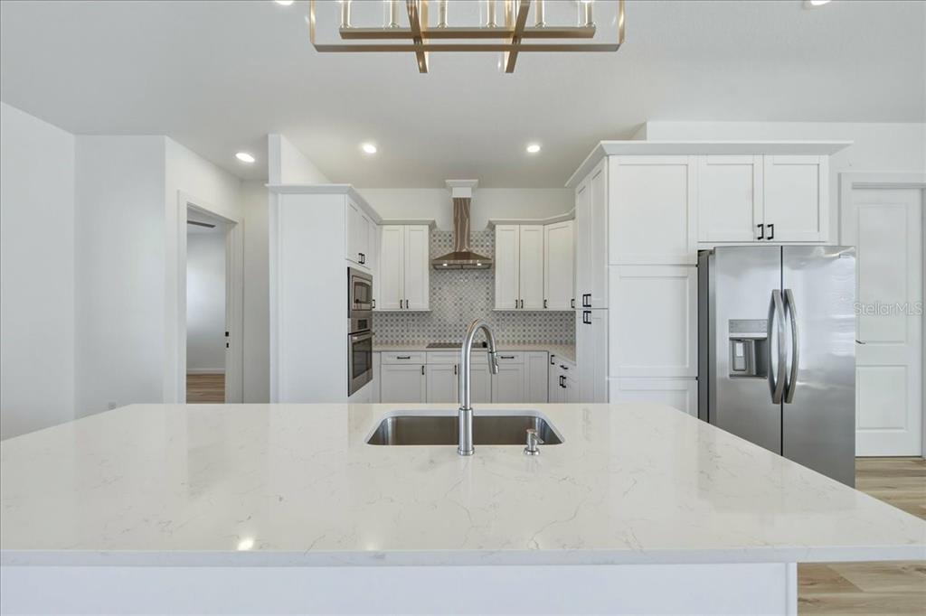 1215 Rio De Janeiro Avenue Punta Gorda, FL 33983 - Photo 36 of 65 a large white kitchen with kitchen island a sink stainless steel appliances and cabinets