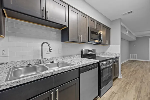 a kitchen with granite countertop a sink stainless steel appliances and cabinets