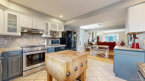 a kitchen with stainless steel appliances granite countertop a stove top oven a sink dishwasher a dining table and chairs with wooden floor