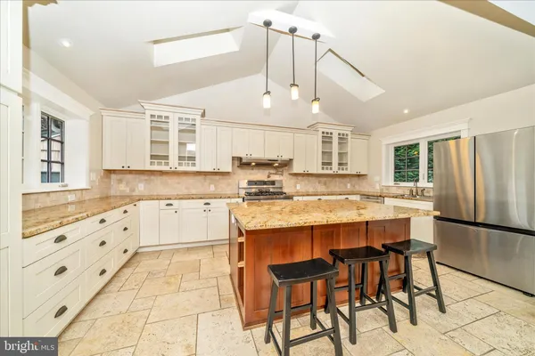 a kitchen with stainless steel appliances kitchen island granite countertop a stove a cabinets and chairs