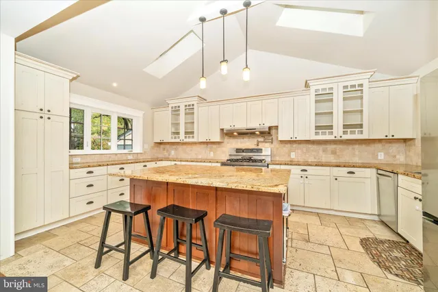 a kitchen with granite countertop a stove a sink and white cabinets with wooden floor