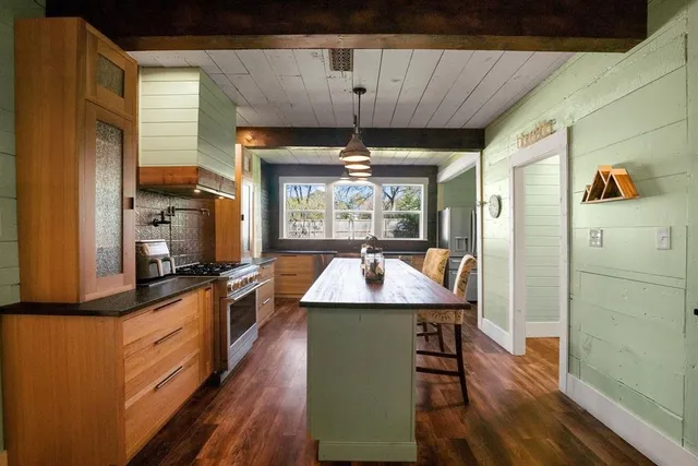 a kitchen with kitchen island granite countertop a refrigerator a stove a sink dishwasher a dining table and chairs with wooden floor