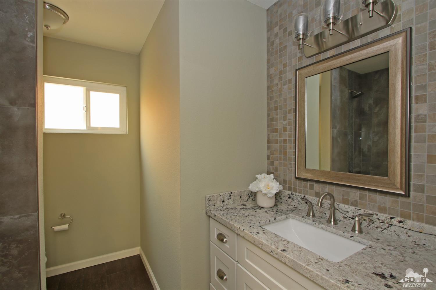 73733 Haystack Road Palm Desert, CA 92260 - Photo 17 of 36 a bathroom with a granite countertop sink a mirror and a vanity