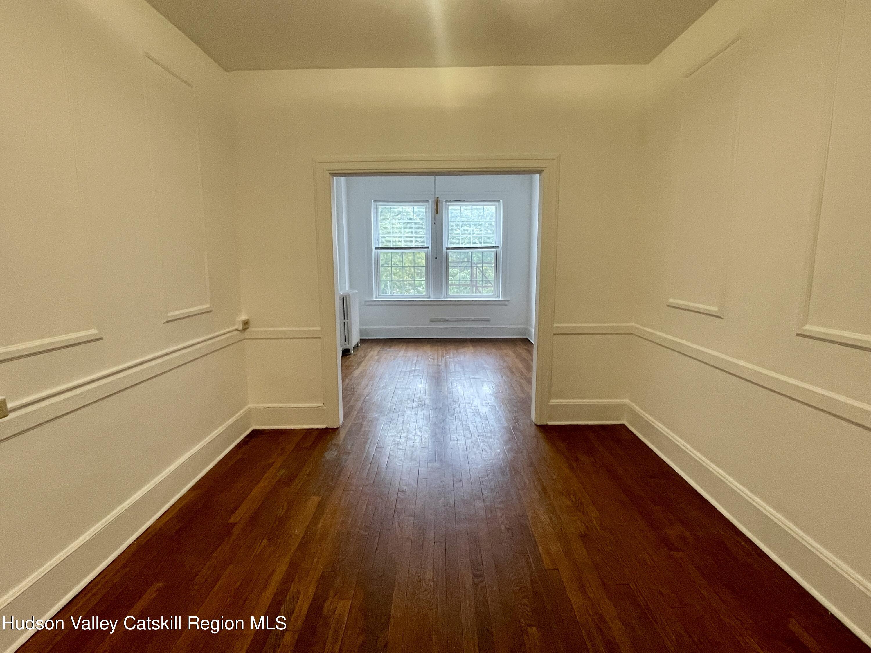 711 Warren Street, Unit 4 Hudson, NY 12534 - Photo 9 of 14 an empty room with wooden floor and windows