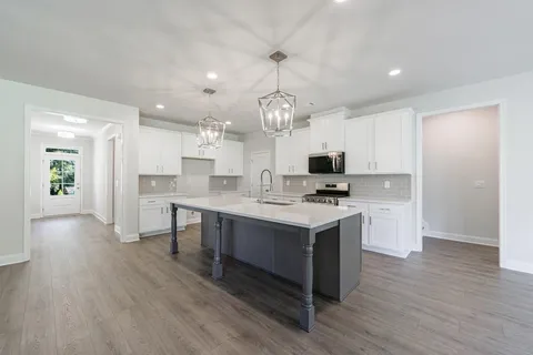 a kitchen with kitchen island granite countertop a sink cabinets and wooden floor