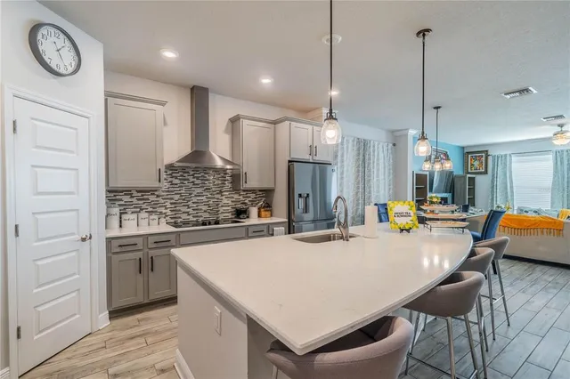 a kitchen with stainless steel appliances granite countertop a sink a refrigerator a stove a kitchen island with a dining table and chairs