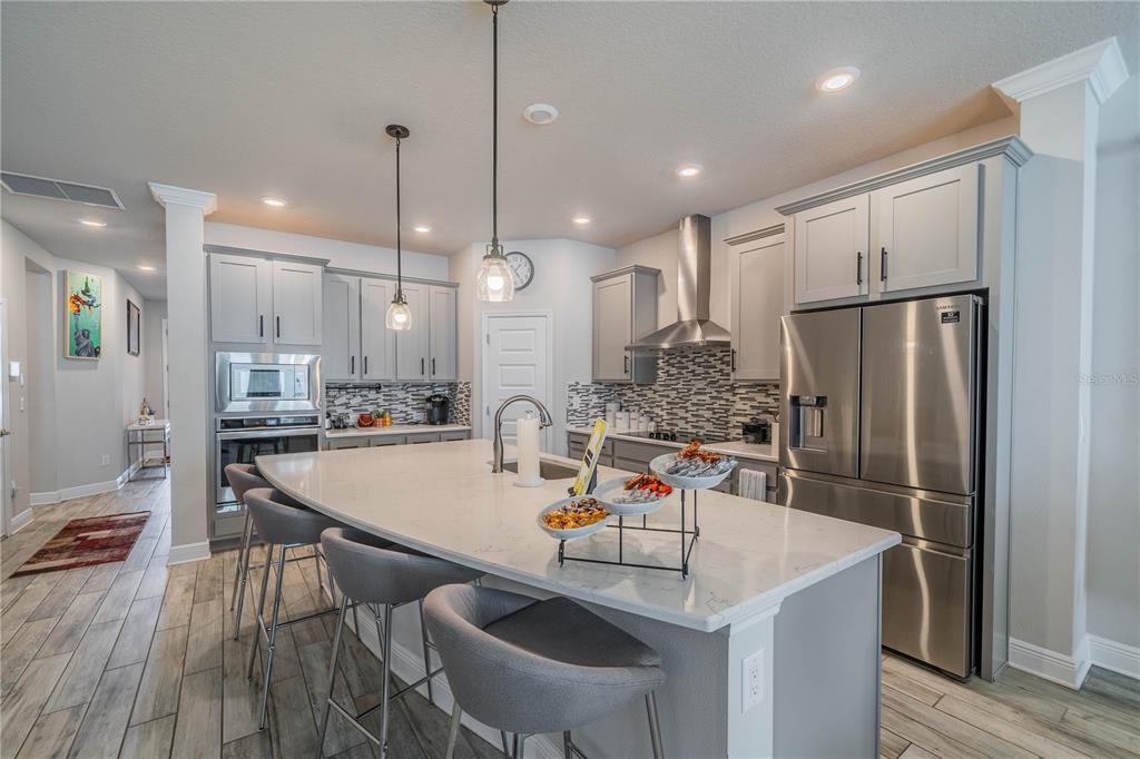 5538 Spanish Moss Cove Bradenton, FL 34203 - Photo 16 of 31 a kitchen with stainless steel appliances granite countertop a sink a refrigerator a stove a kitchen island with a dining table and chairs