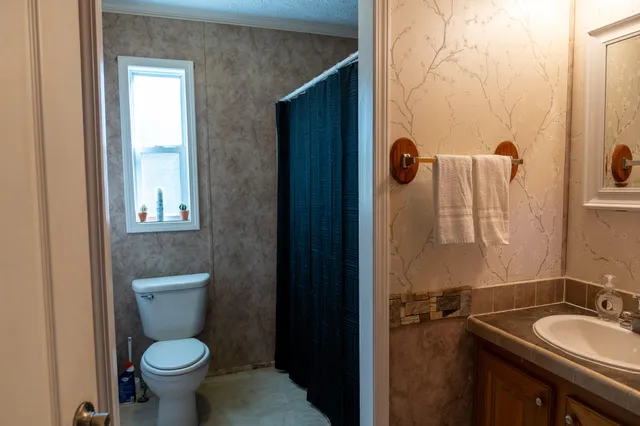 a bathroom with a granite countertop toilet and a sink