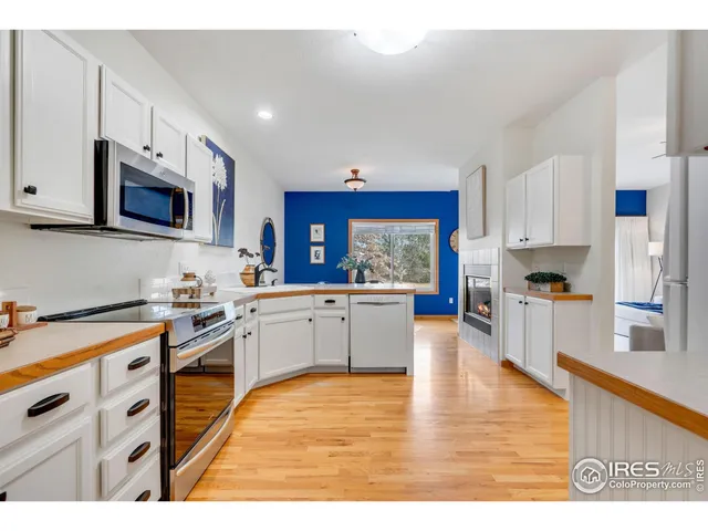 a kitchen with stainless steel appliances granite countertop a stove top oven a sink a refrigerator white cabinets and wooden floor