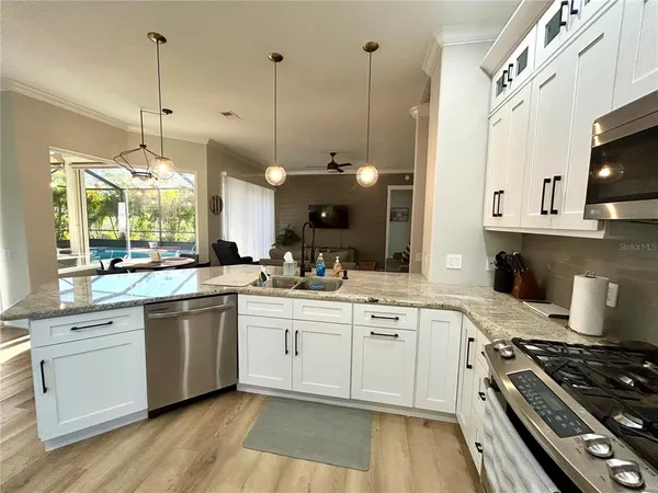 a open kitchen with stainless steel appliances granite countertop a stove a sink and white cabinets