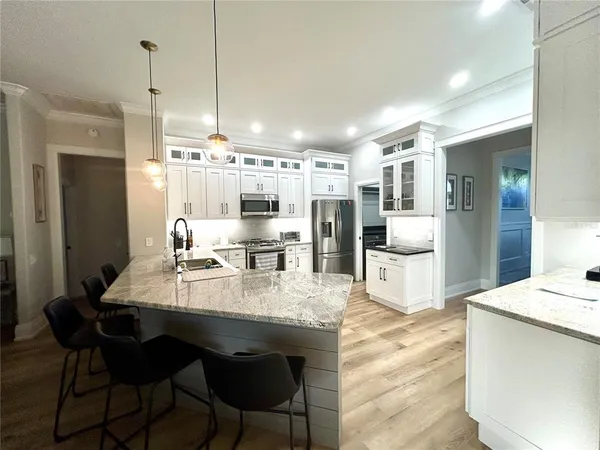 a large kitchen with sink a refrigerator and chairs