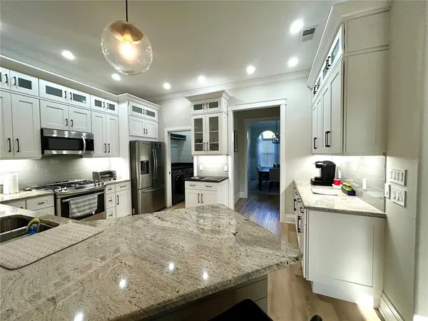 a kitchen with stainless steel appliances kitchen island granite countertop a stove refrigerator and cabinets