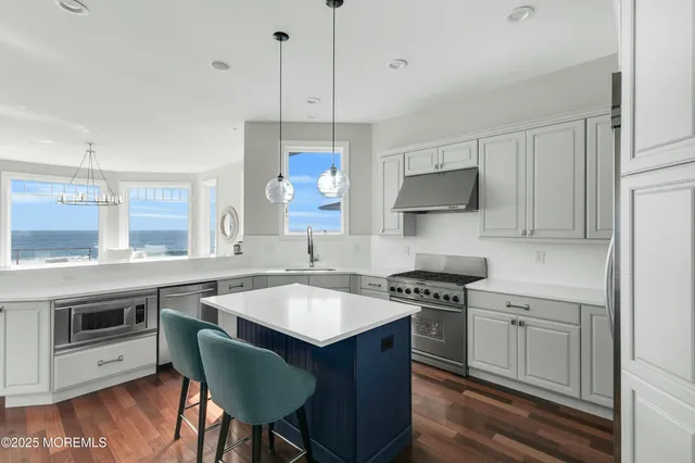 a kitchen with stainless steel appliances a refrigerator a sink dishwasher a oven with wooden cabinets and floor