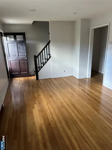 a view of an empty room with wooden floor and stairs