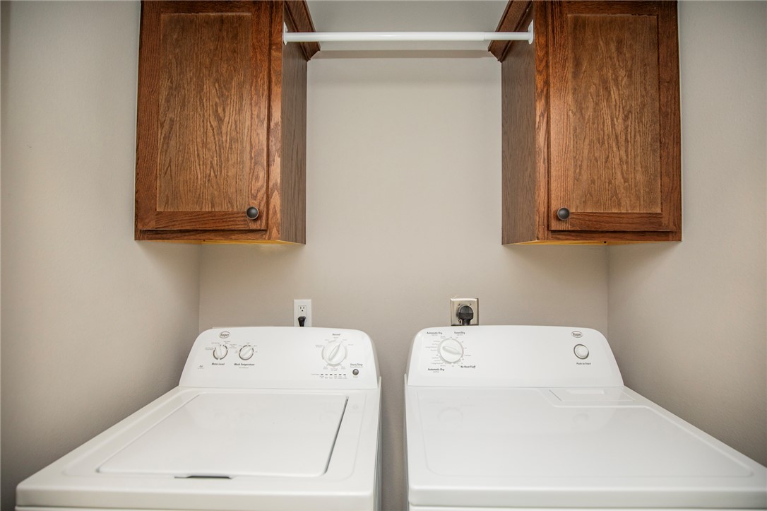 214 Alder Street Pea Ridge, AR 72751 - Photo 18 of 20 Dedicated laundry area featuring dual upper wood-finish cabinetry, a white hanging rod, and light-toned wall paint