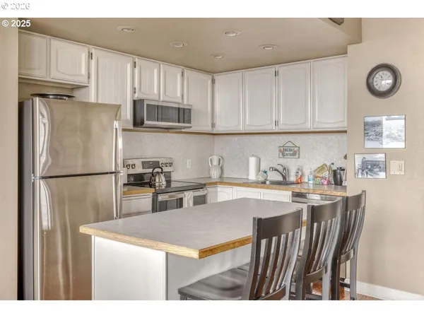 a kitchen with stainless steel appliances a refrigerator a stove a sink dishwasher with a dining table and chairs