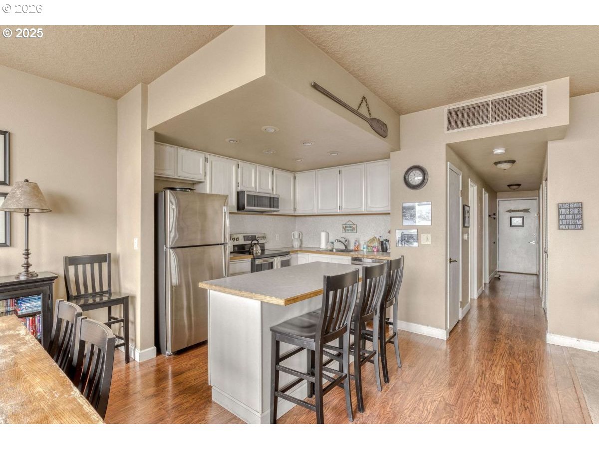 475 South Promenade, Unit 518 Seaside, OR 97138 - Photo 16 of 29 a kitchen with stainless steel appliances a refrigerator a stove a sink dishwasher with a dining table and chairs