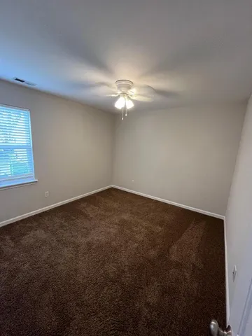 an empty room with a fan & a window