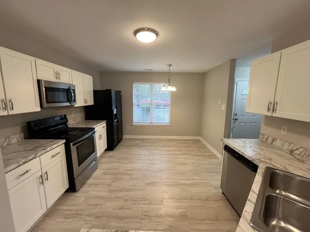 a kitchen with kitchen island granite countertop a stove top oven a sink dishwasher a dining table and chairs with wooden floor