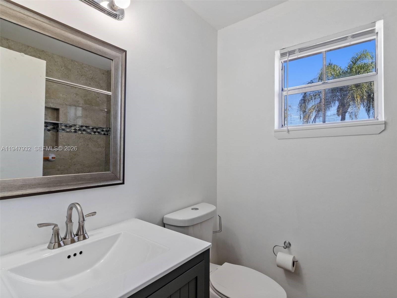 9066 Southwest 147th Court Miami, FL 33196 - Photo 22 of 31 a bathroom with a toilet a sink and mirror