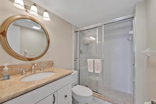 a bathroom with a granite countertop sink toilet mirror vanity and shower
