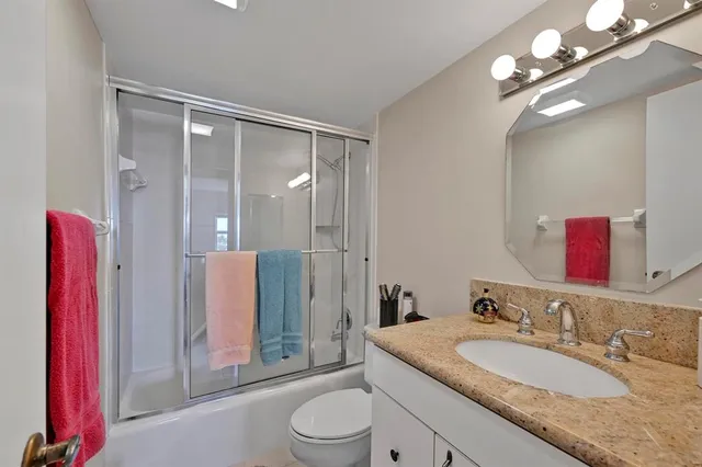a bathroom with a granite countertop sink a toilet a mirror and shower