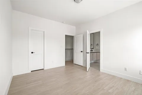 a view of an empty room with wooden floor and closet