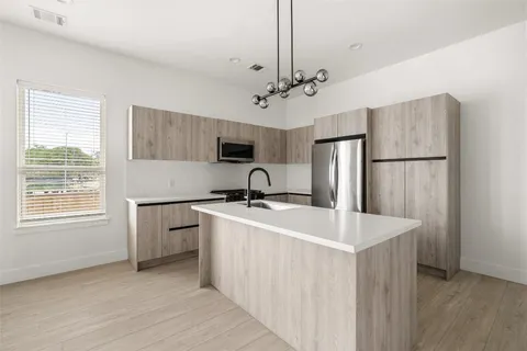 a kitchen with kitchen island a sink appliances a counter space and a window