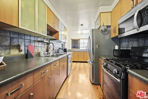 a kitchen with stainless steel appliances granite countertop a sink a stove and a wooden floors