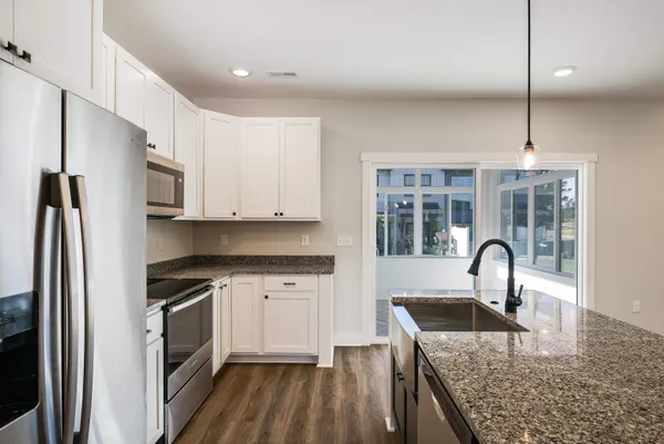 a kitchen with stainless steel appliances granite countertop a sink a window and wooden floor