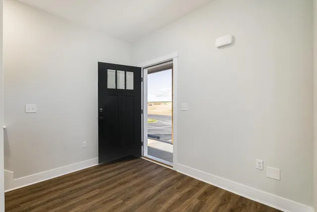 a kitchen with kitchen island granite countertop stainless steel appliances a refrigerator a sink a stove cabinets and wooden floor