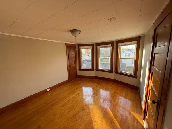 a view of an empty room with a window and wooden floor