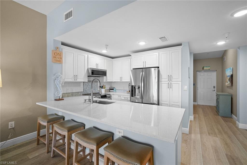 4455 Botanical Pl Circle, Unit 405 Naples, FL 34112 - Photo 5 of 46 a kitchen with refrigerator and chairs