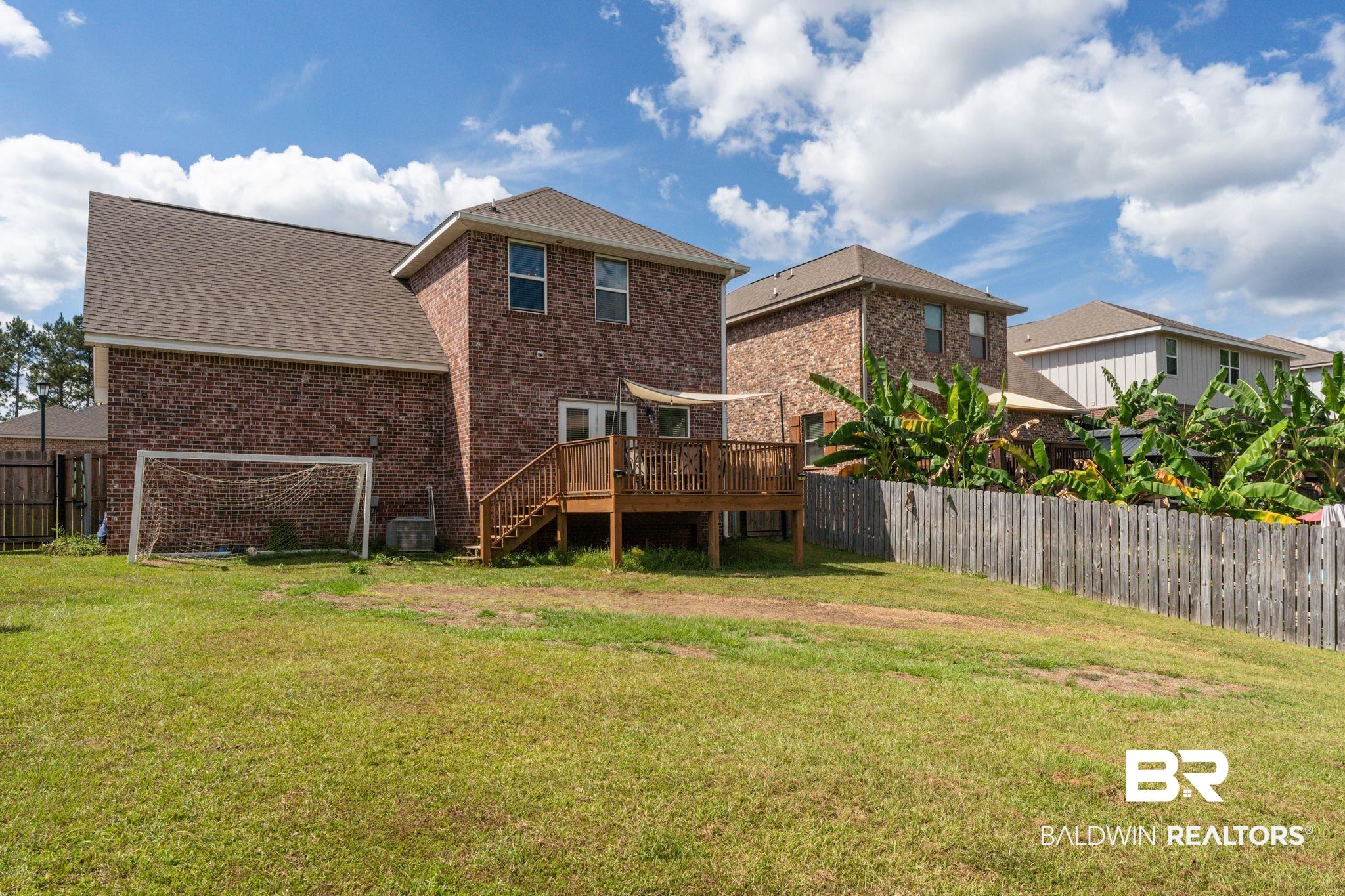 12711 Chickadee Lane Daphne, AL 36527 - Photo 31 of 39 Back of property with a fenced backyard, a deck, brick siding, stairway, and a shingled roof
