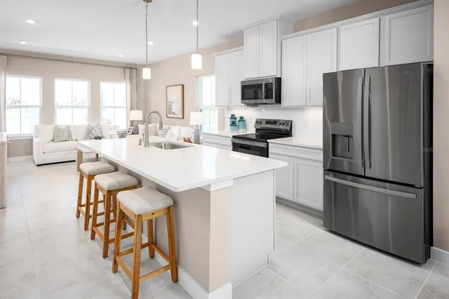 a kitchen with stainless steel appliances a refrigerator a stove a dining table and chairs