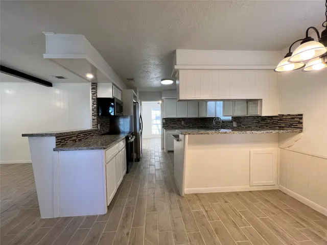 a kitchen with stainless steel appliances granite countertop a refrigerator and a stove top oven
