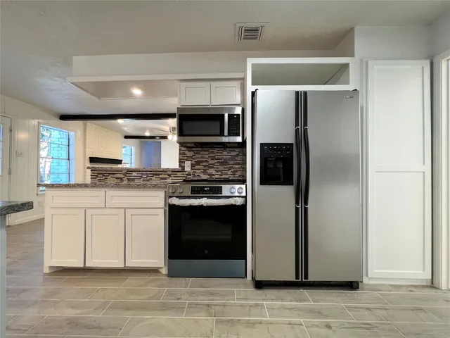 a kitchen with stainless steel appliances white cabinets and a stove top oven