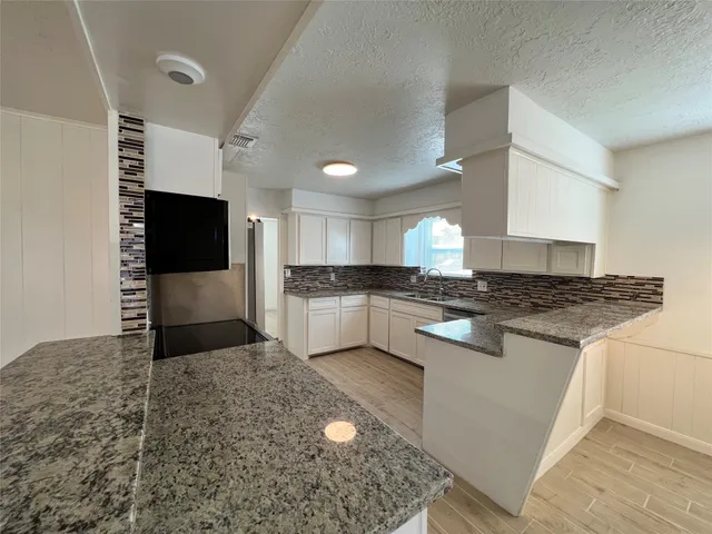 an empty room with a chandelier fan and windows