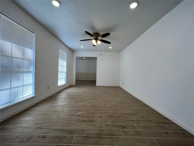an empty room with wooden floor fireplace and windows